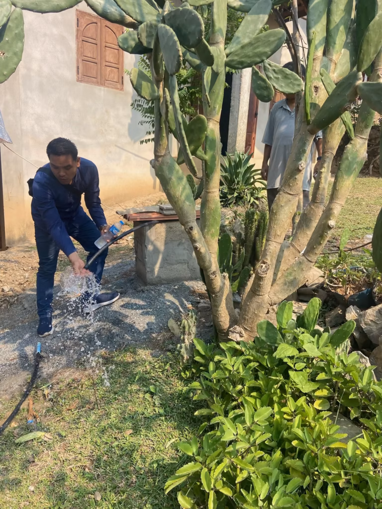 A man splashes clean water flowing from the new well line outside a village home