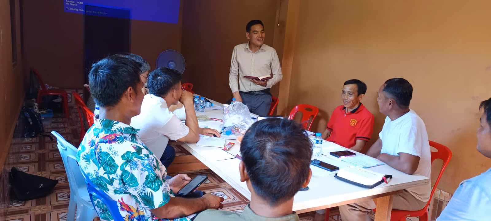 Pastor Khen Teaching From the Bible at a Table in Laos